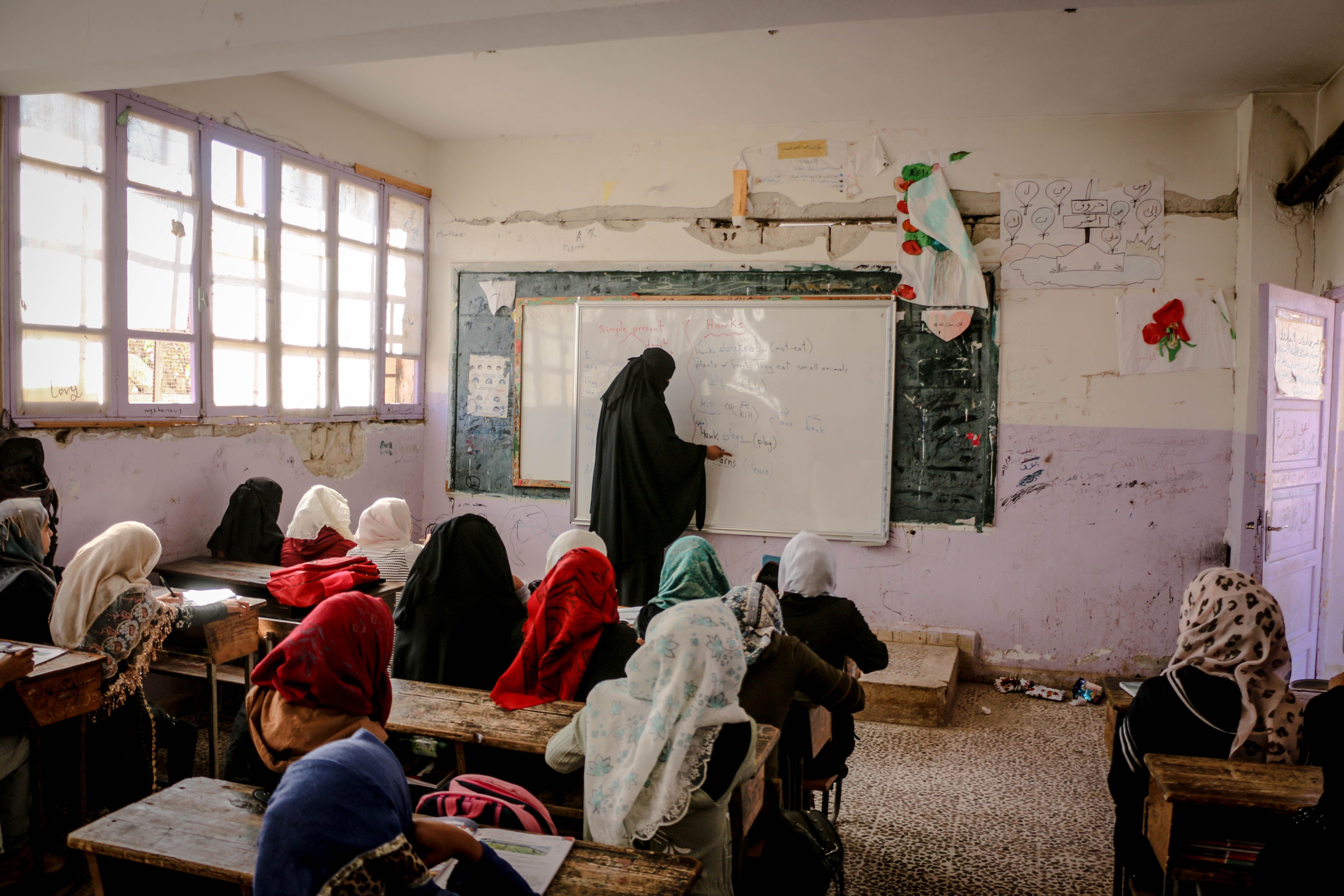 Teacher guiding a class of young Muslim students during a lesson, fostering a caring and focused environment.