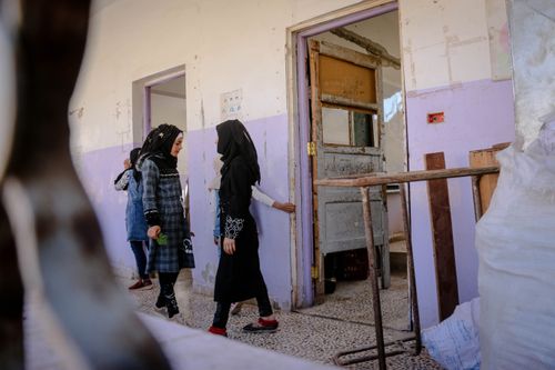 Free Children in traditional clothing entering a school building in Idlib, Syria, showcasing cultural heritage. Stock Photo