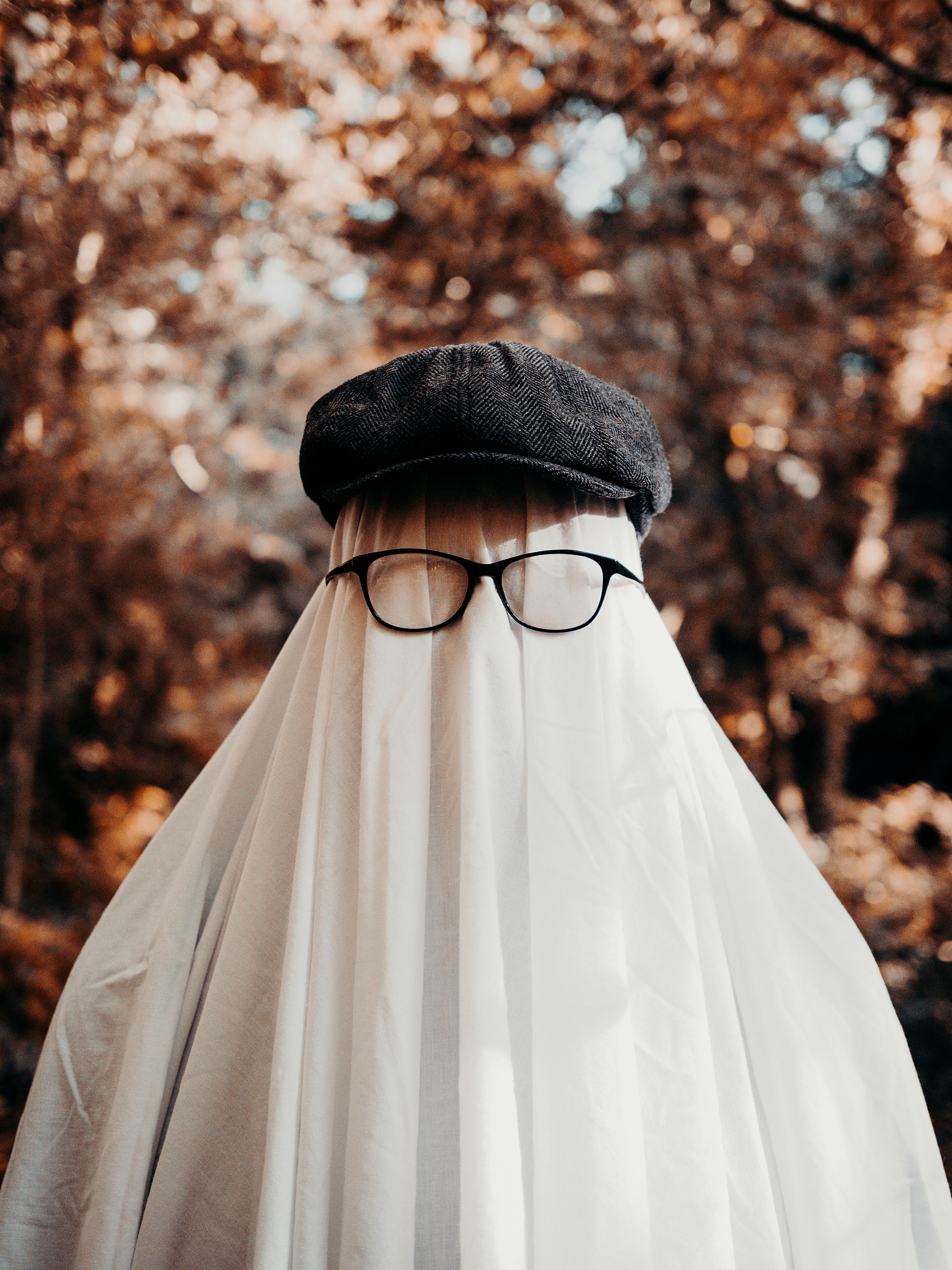 Creative Halloween ghost costume with a cap and glasses in a forest setting, perfect for spooky themes.