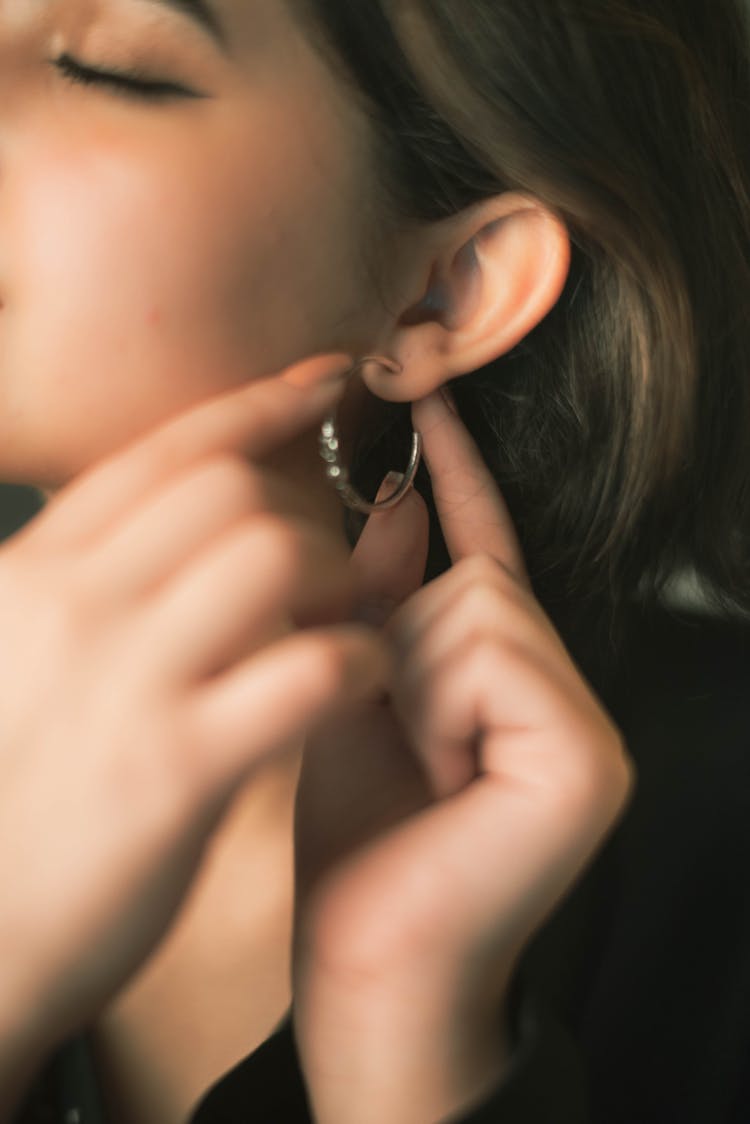 Close-up Photo Of Woman Putting Earings