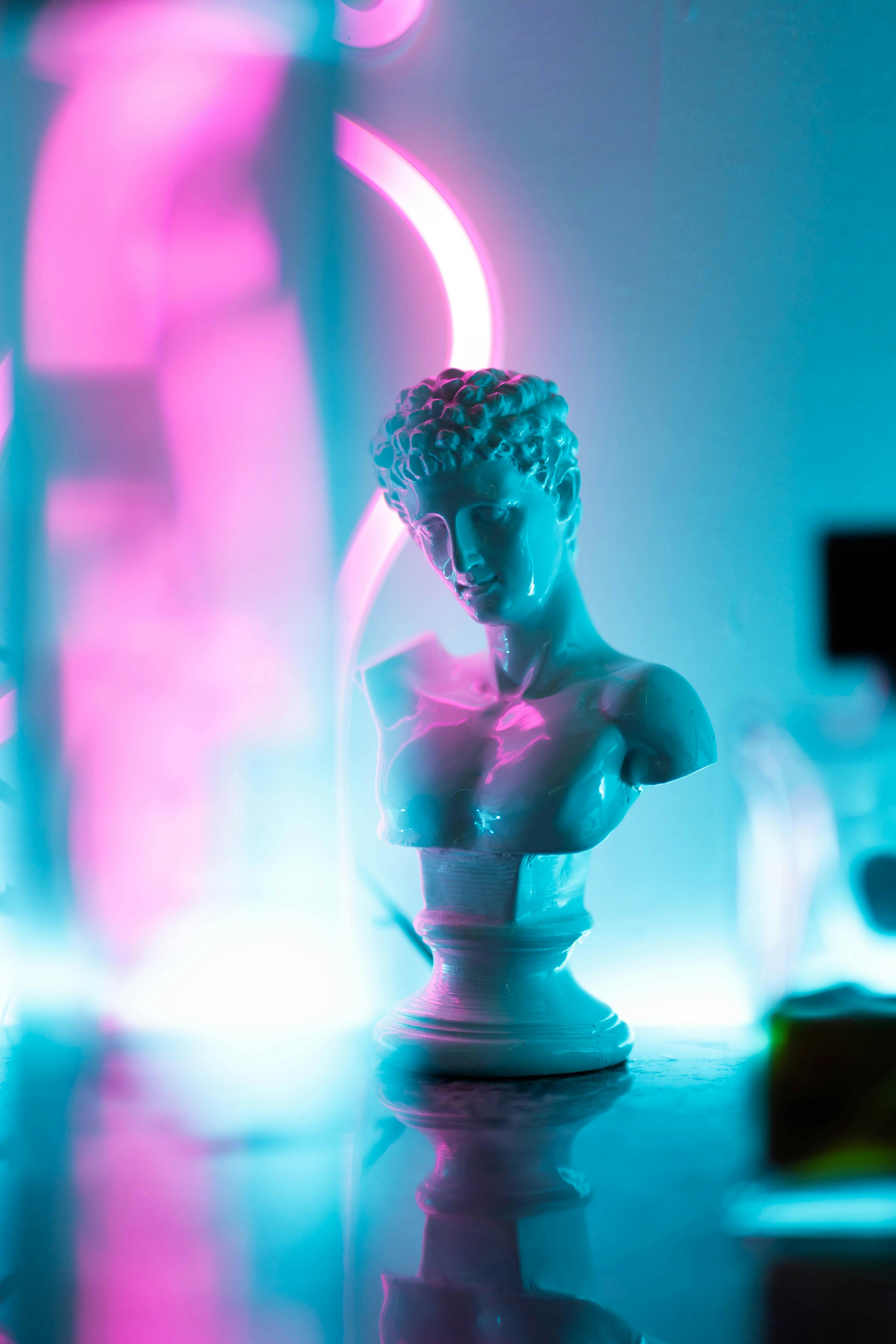 Classical bust statue with neon pink and blue lighting, creating a futuristic artistic effect.