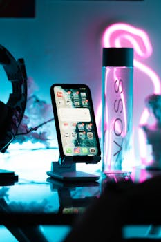 A stylish smartphone displayed against a neon-lit background, featuring a Voss water bottle.