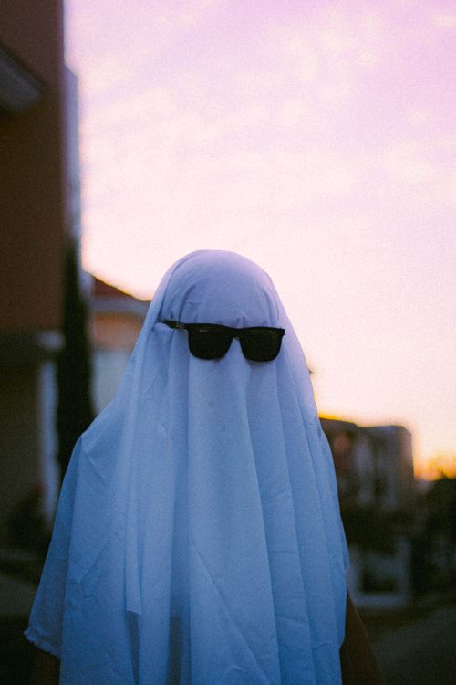 Free A figure shrouded in white fabric and sunglasses creating a mysterious vibe at twilight. Stock Photo
