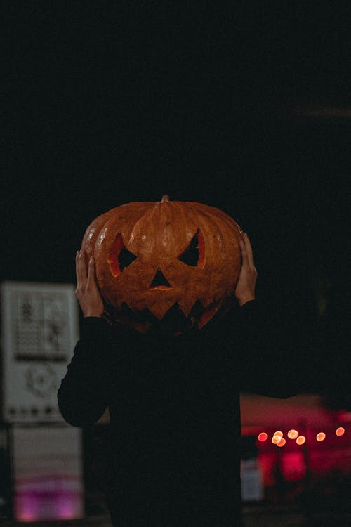 Person Wearing a Jack O Lantern on Black Background