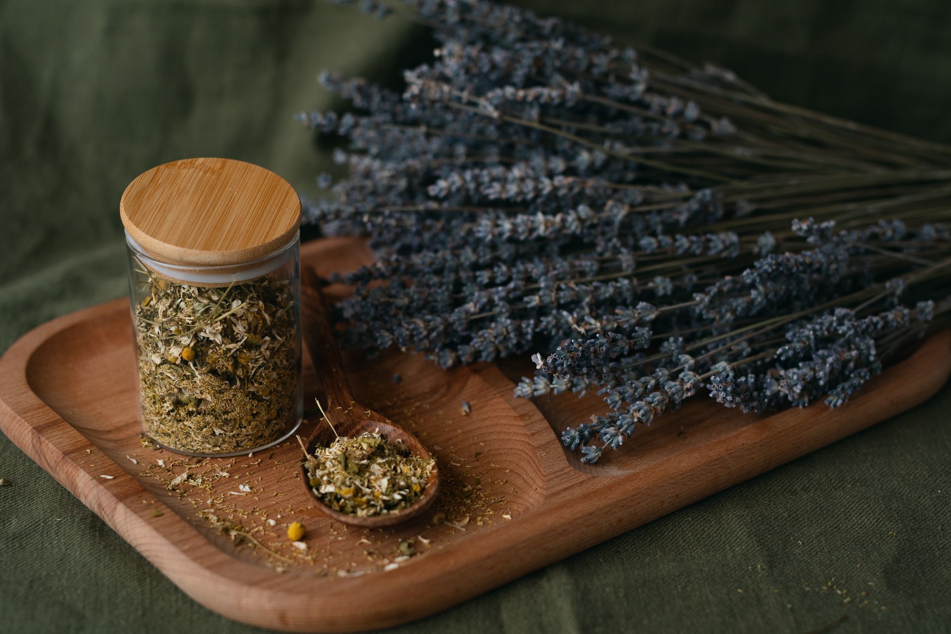 Still life of dried lavender and herbal mix in a jar and on a wooden board.