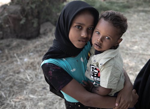 Photo of a Girl Carrying Her Brother