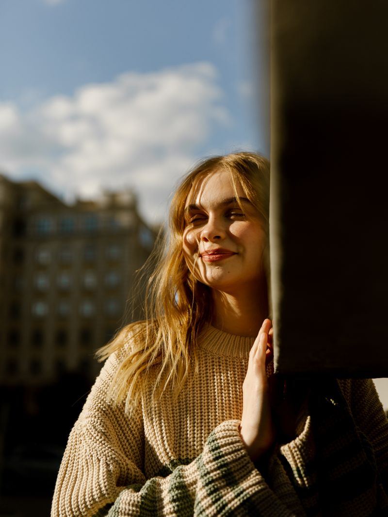 Woman with long wavy blonde hair in a cream sweater