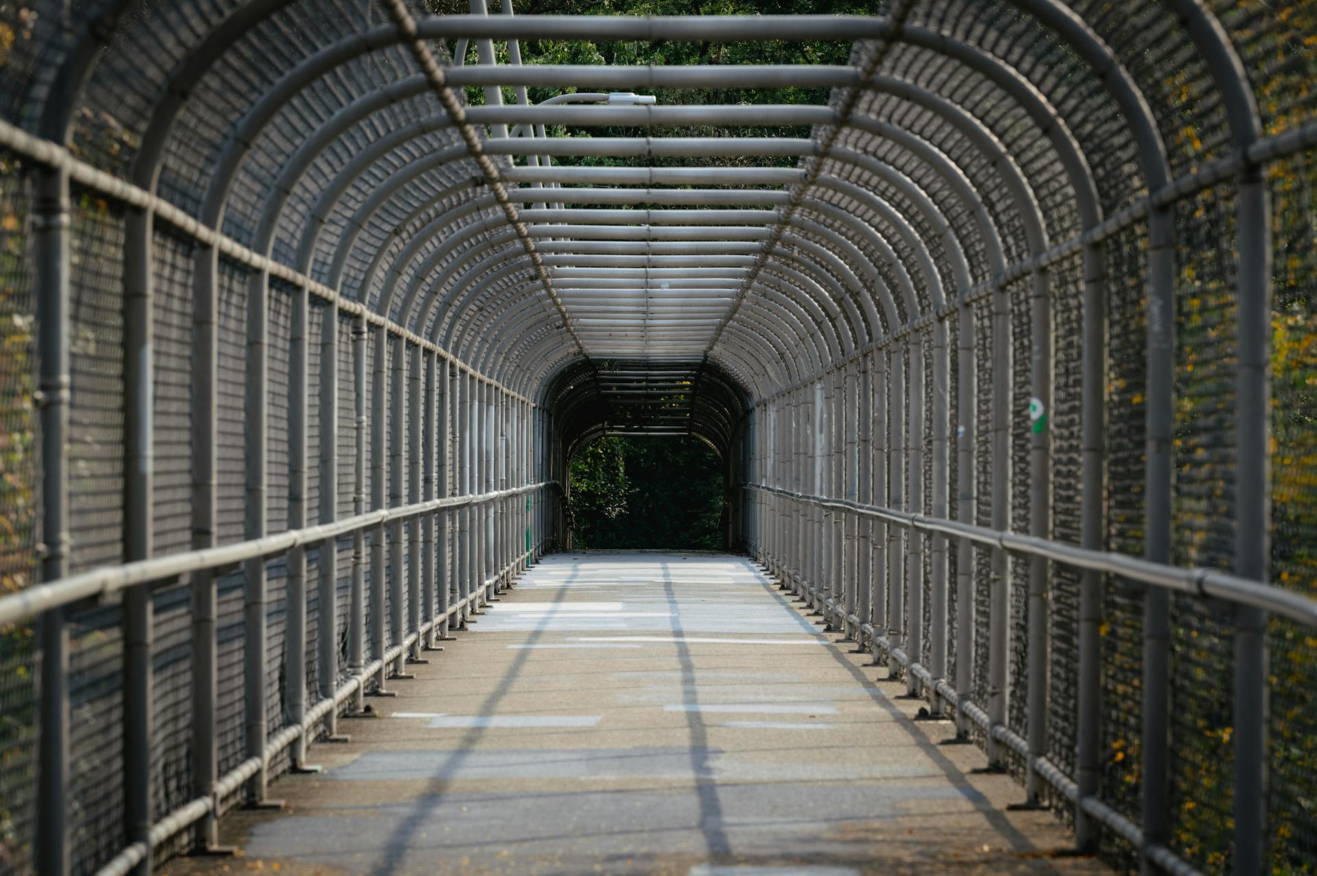 Symmetrical enclosed pedestrian bridge overpass with steel construction and a clear walkway.