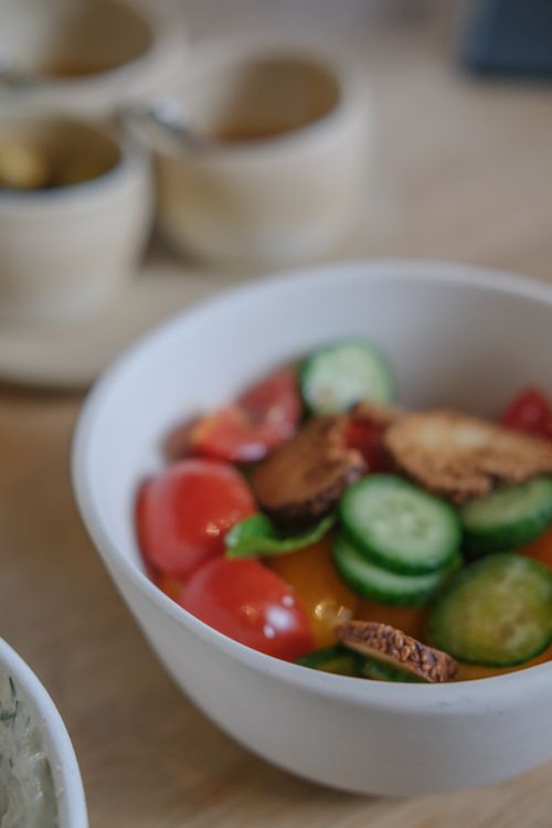 Free Close-up of a fresh vegetable salad with cucumbers, tomatoes, and crispy bread in a white bowl. Stock Photo