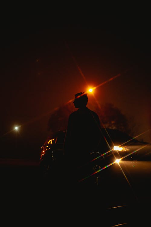 A Silhouette of a Male Next to a Car During Night Time · Free Stock Photo