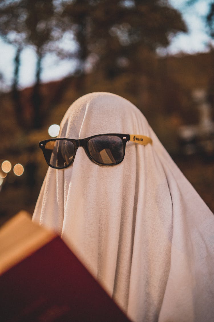 Person Wearing Sunglasses Over White Sheet