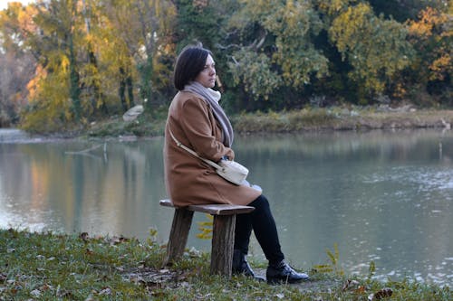 Alone Woman sitting on Wooden Bench on a Lakeside 