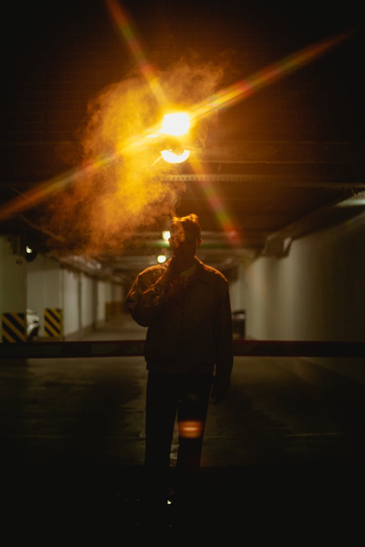 A Silhouette Of A Male Smoking A Cigarette And Walking Towards Camera 