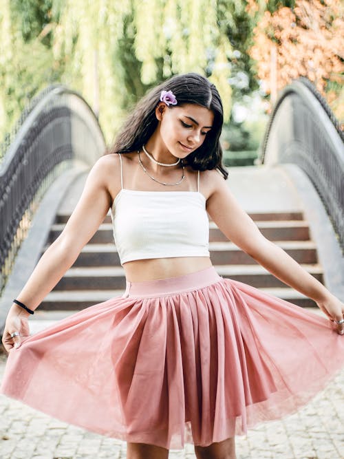 A Woman in White Tank Top and Pink Skirt Looking Down