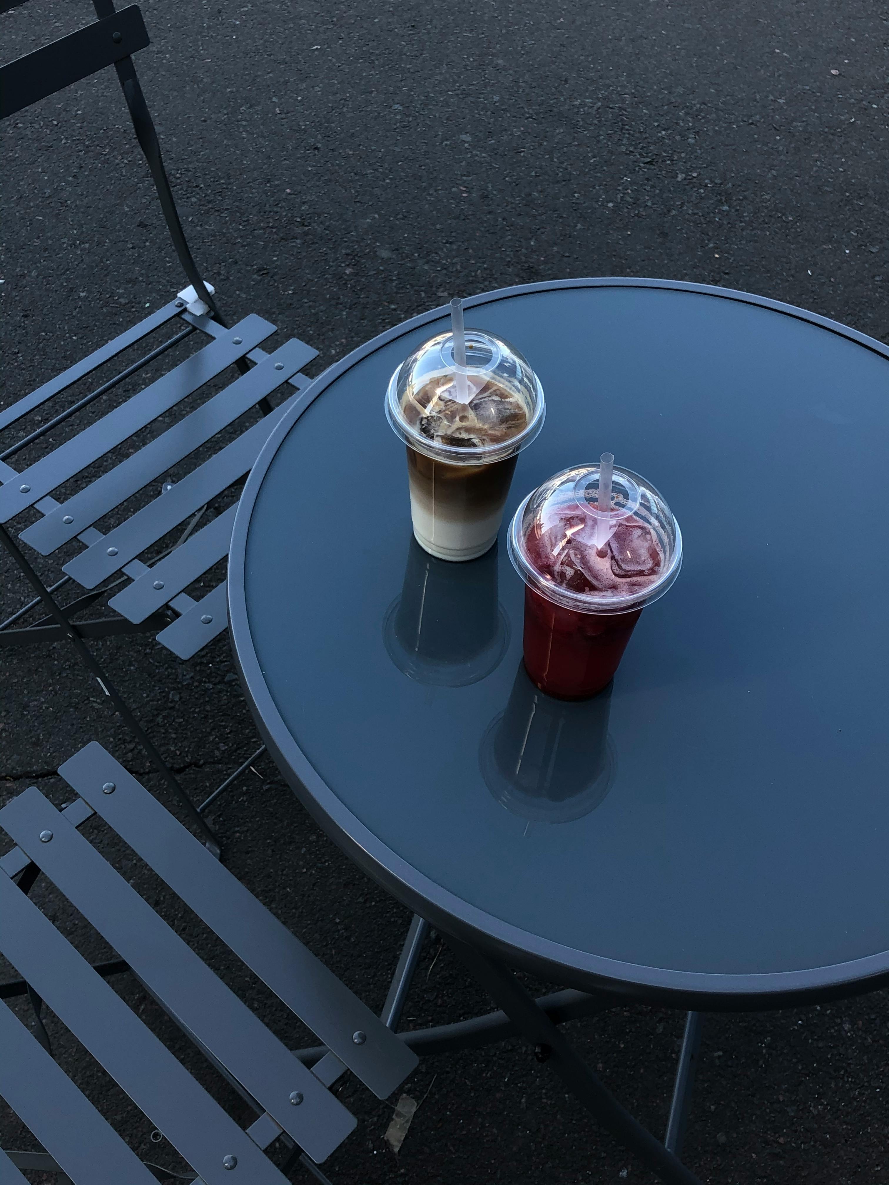 Two iced drinks, coffee and juice, on an outdoor metal table in Odessa.