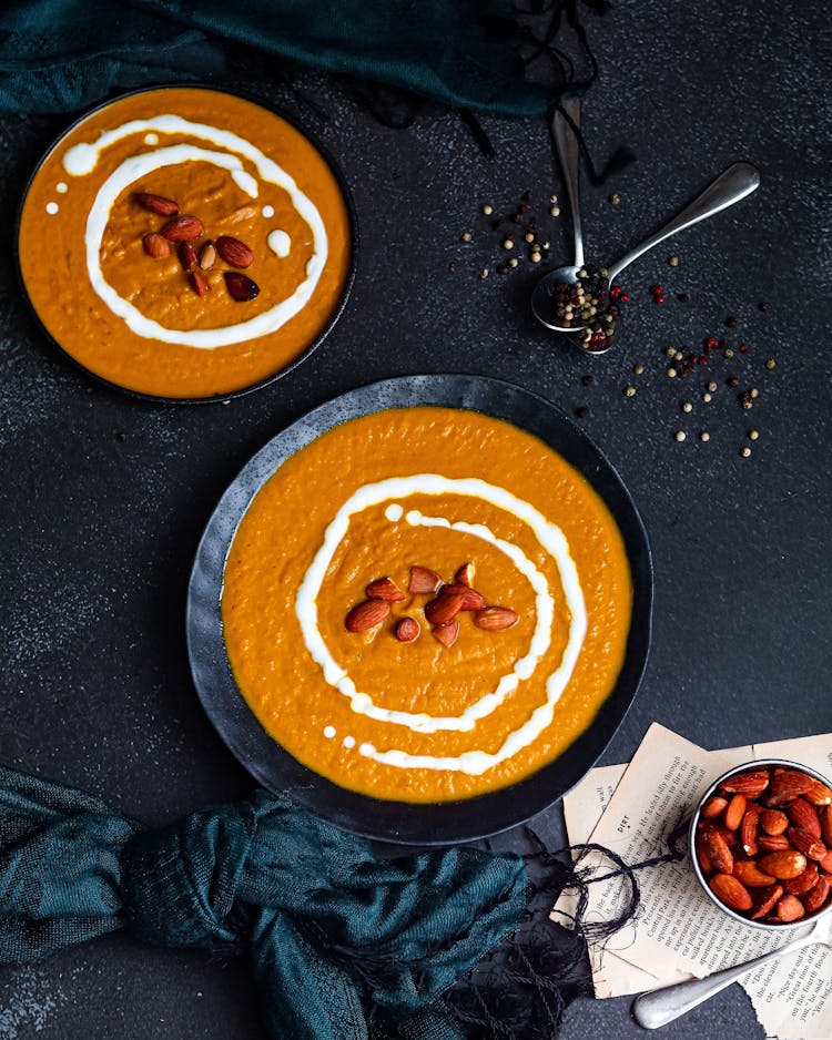 A Soup On Black Bowls With Almonds On Top