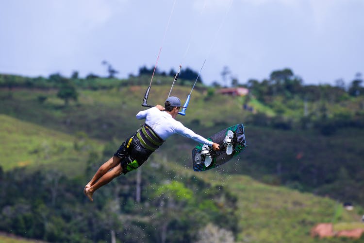 Flying Kite Surfer Holding Surfboard In Hand