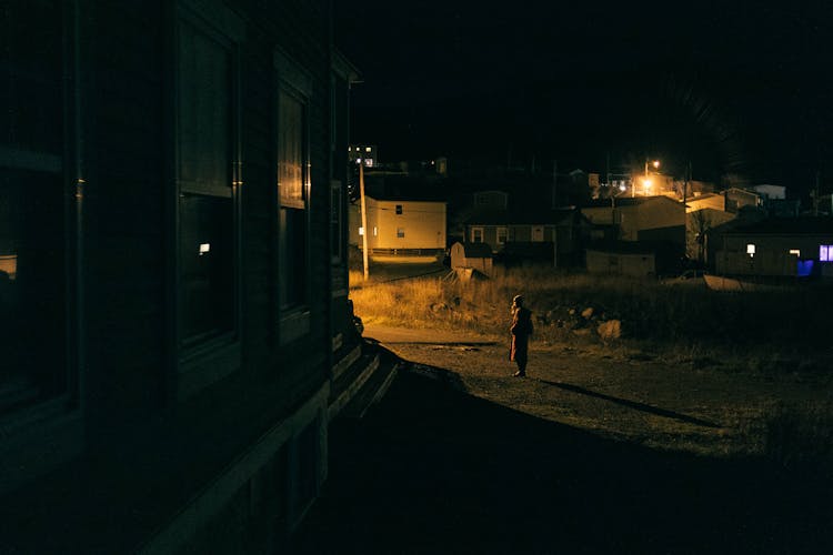 Person Standing On A Neighborhood During Nighttime 