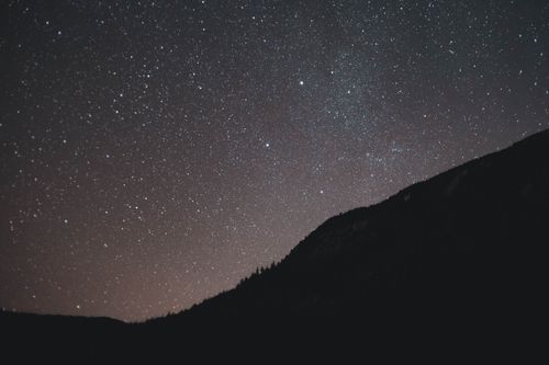 Free A breathtaking view of the starry night sky with a silhouetted mountain range. Stock Photo