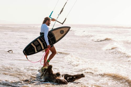Free Kitesurfer riding waves on the sea with a surfboard, showcasing extreme sports action. Stock Photo