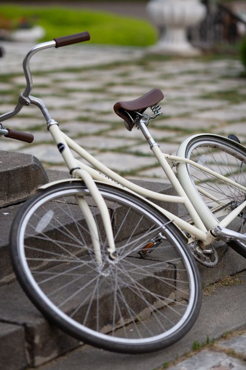 Free A vintage white bicycle leaning on stone steps in an outdoor setting. Perfect for urban lifestyle themes. Stock Photo