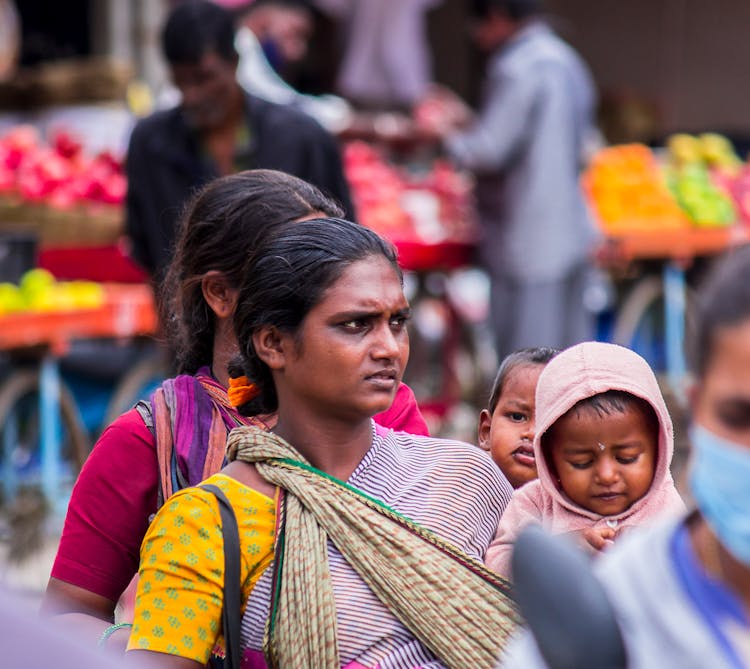 Woman Walking Through A Market Holding Her Child