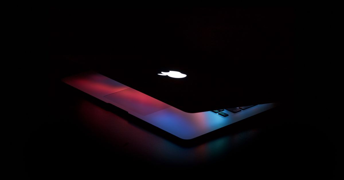 A laptop glowing with a dashboard interface in a dark room
