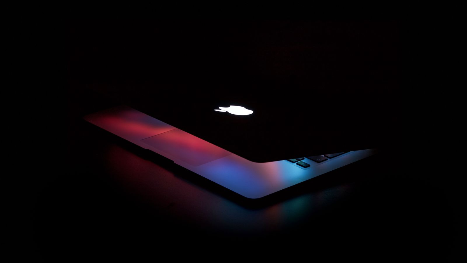 A laptop glowing with a dashboard interface in a dark room