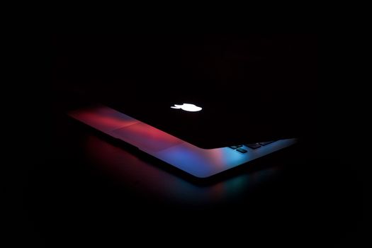 Captivating close-up of a partially open laptop with colorful lighting against a dark background.