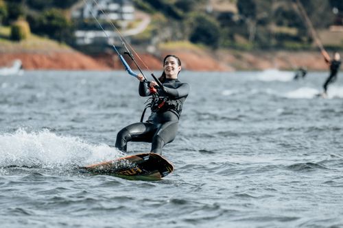 Free A smiling woman enjoying kiteboarding on the ocean, showcasing freedom and fun. Stock Photo