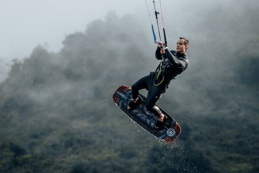 Action shot of a kitesurfer in midair against a foggy backdrop, showcasing extreme sports.