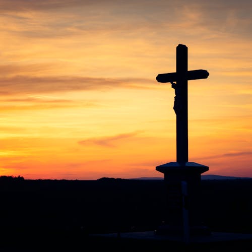 Silhouette of Cross against Dramatic Sky at Dusk