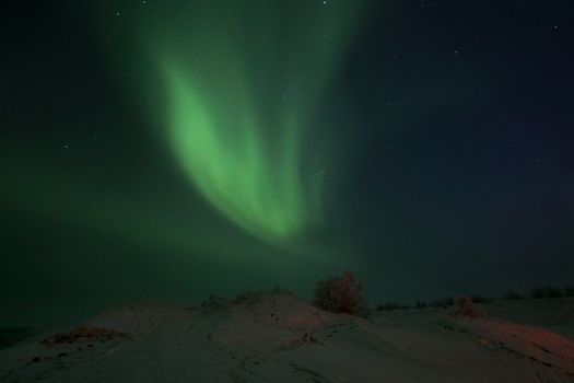 Stunning view of aurora borealis illuminating a snowy landscape at night.