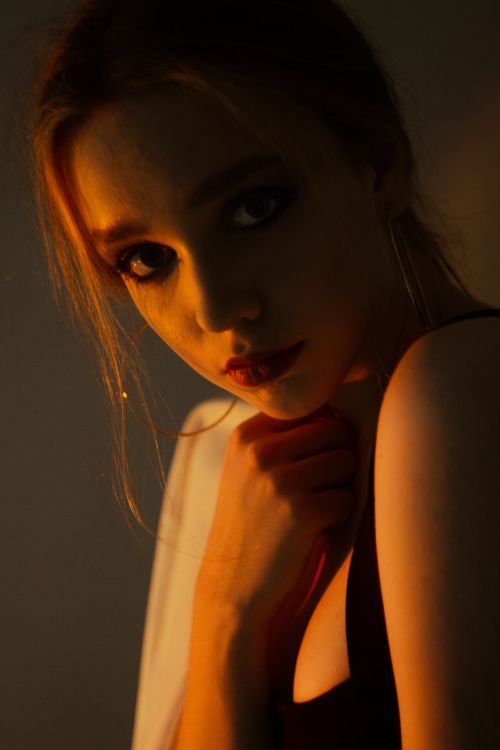 Free A woman's dramatic close-up portrait in warm, moody lighting. Stock Photo
