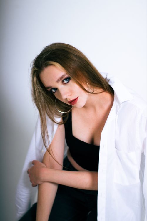 Free Elegant portrait of a young woman with brown hair wearing a white shirt and black top. Stock Photo