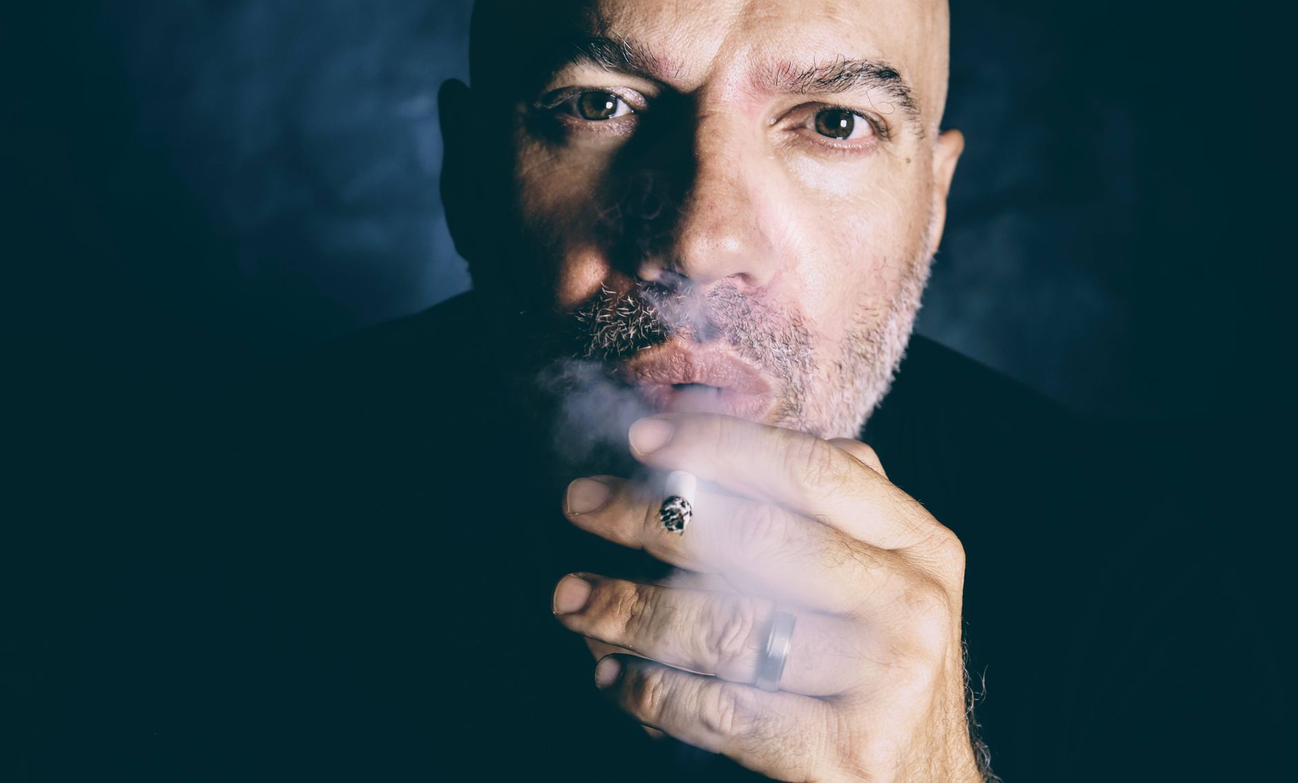 Close-up portrait of a man smoking, emphasizing addiction themes.