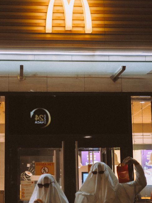 People dressed as ghosts in front of a McDonald's, capturing a blend of fun and spooky vibes.