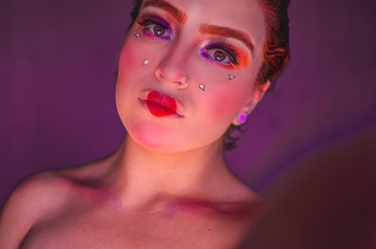 Vibrant portrait of a woman with artistic makeup under colorful lighting, creating a bold and modern look.