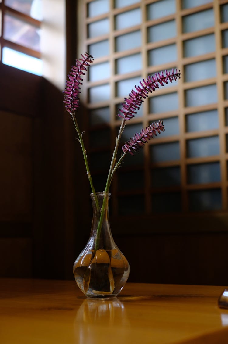 Glass Vase With Few Flowers On Table 