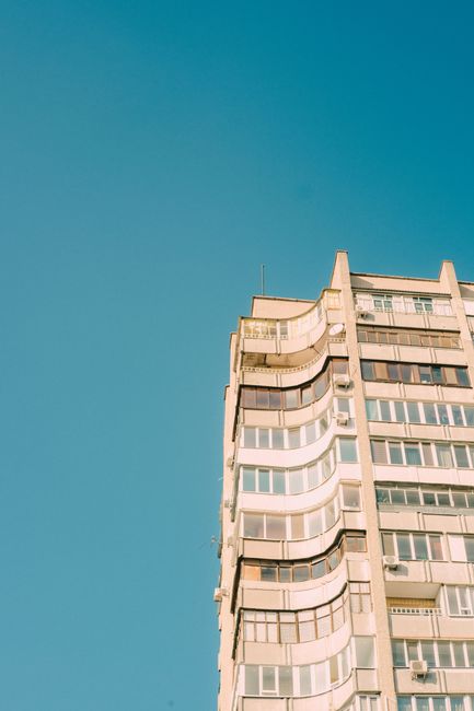 High-rise apartment building against a vibrant blue sky, capturing modern urban architecture.