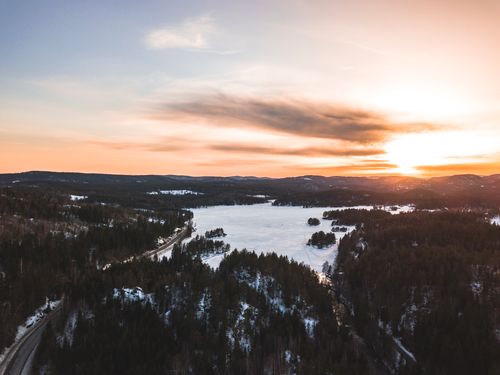 Free Stunning aerial view of a snowy forest landscape at sunset, showcasing winter beauty and serene nature. Stock Photo