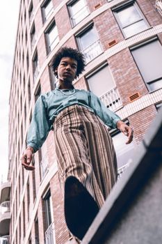 A stylish person poses in a city setting with modern architecture.
