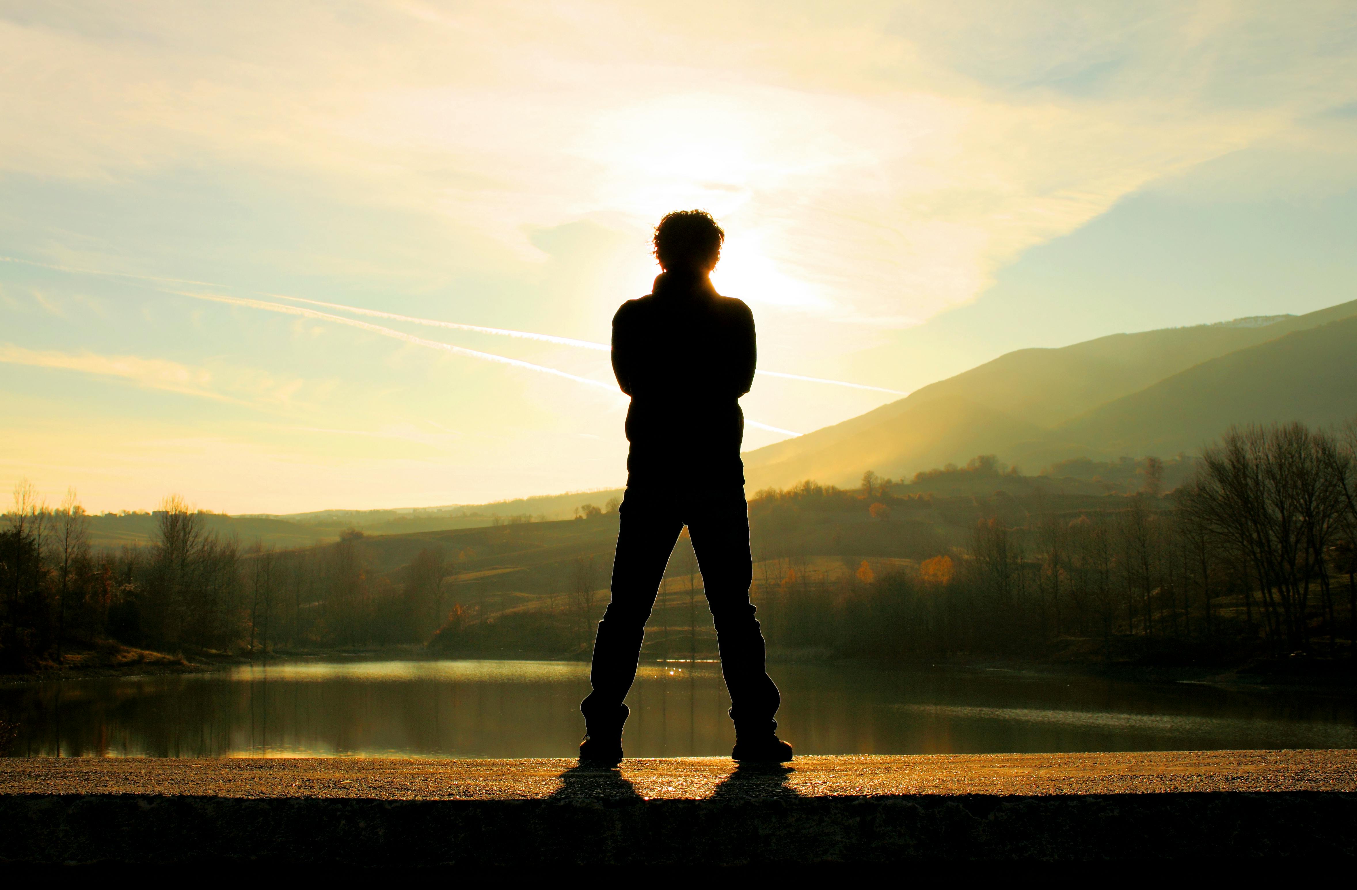 man in black jacket standing near lake