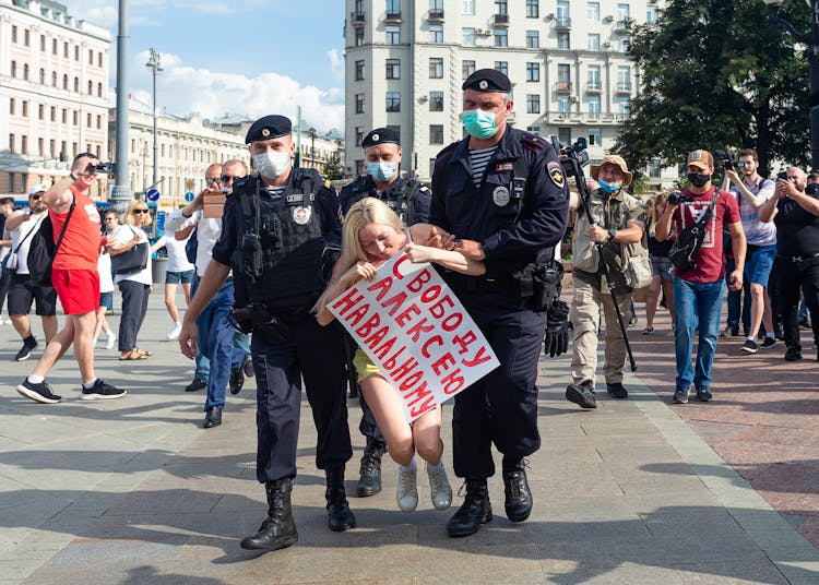 Police Officers Carrying A Female Protester 