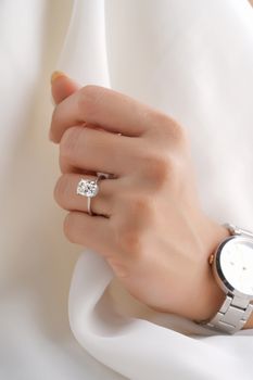Close-up of a hand wearing a diamond ring and stylish wristwatch, showcasing elegance.