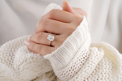 Free Close-up of a sparkling diamond engagement ring on a woman's hand wrapped in a cozy sweater. Stock Photo