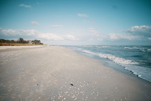 Free A serene beach scene with gentle waves, blue sky, and soft white sand. Stock Photo