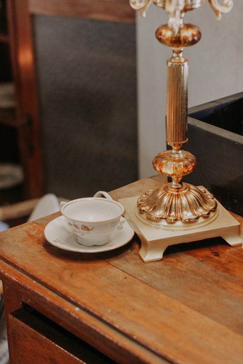 Free Close-up of an elegant teacup beside a vintage lamp on a rustic wooden table. Stock Photo