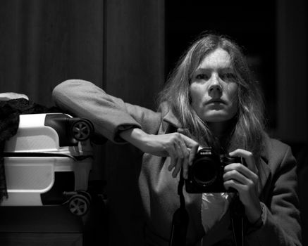 Black and white portrait of a woman holding a camera, intense expression.