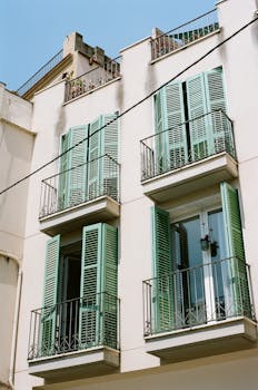 Elegant urban townhouse facade featuring green shutters and balconies.